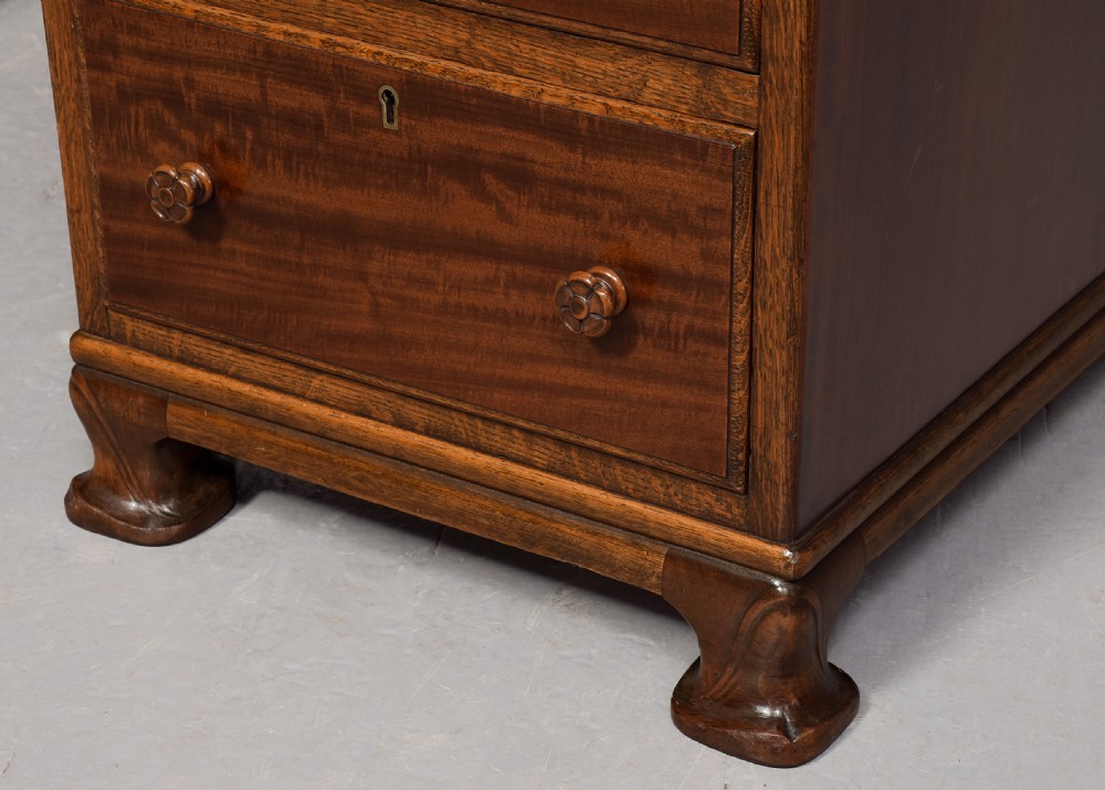 A mahogany three-part pedestal desk featuring a three-panel leather inset top, flame mahogany drawer fronts, turned wooden knobs, and bracket feet. View VI
