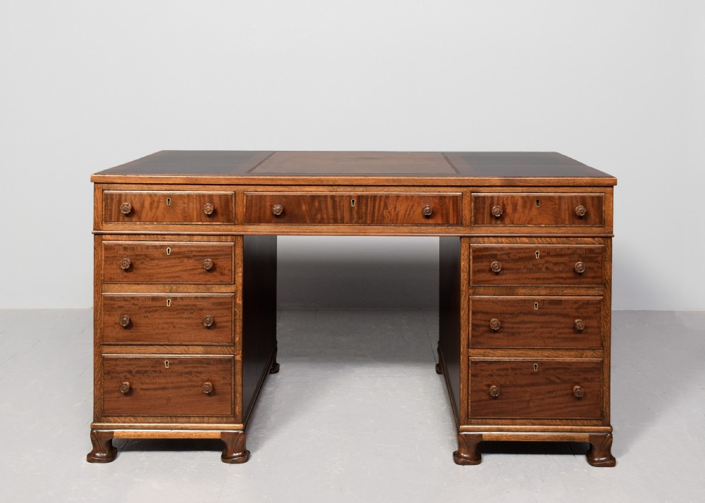 A mahogany three-part pedestal desk featuring a three-panel leather inset top, flame mahogany drawer fronts, turned wooden knobs, and bracket feet. View VII