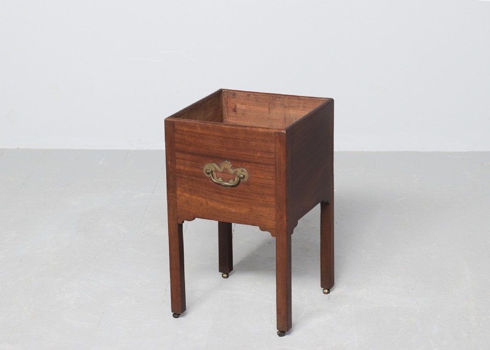 A late Georgian mahogany wine cooler featuring a square open top, side brass handle, straight square legs, and small brass castors. View II