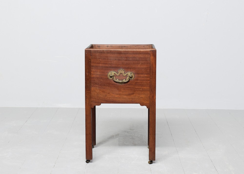 A late Georgian mahogany wine cooler featuring a square open top, side brass handle, straight square legs, and small brass castors. View IV