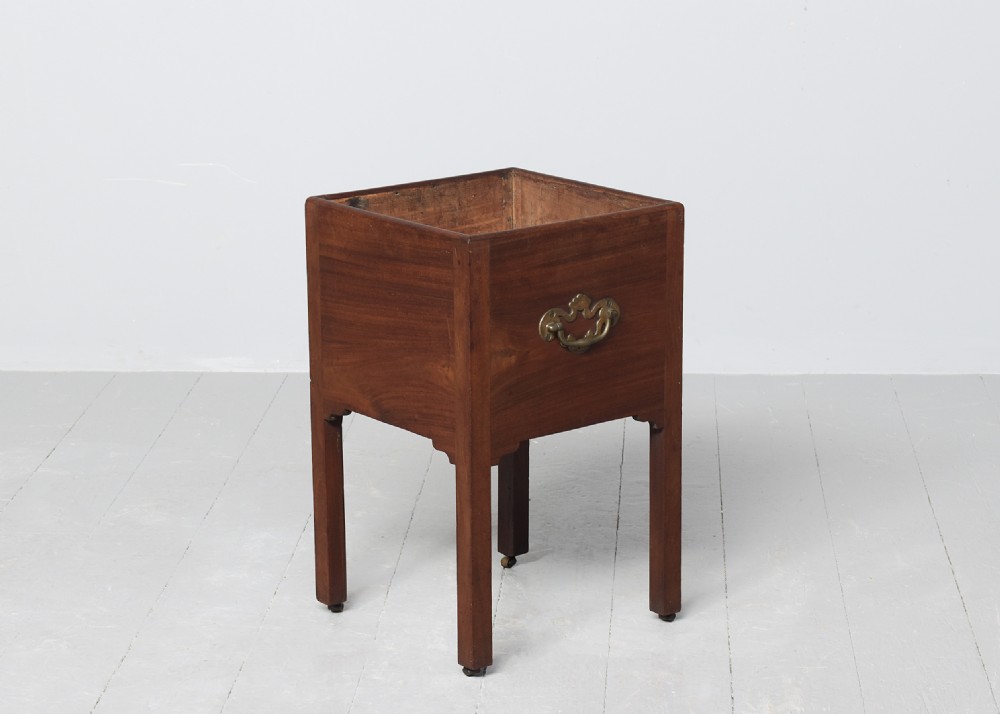 A late Georgian mahogany wine cooler featuring a square open top, side brass handle, straight square legs, and small brass castors. View V