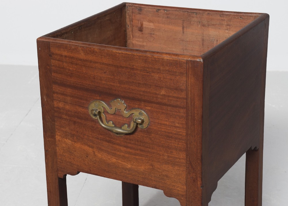 A late Georgian mahogany wine cooler featuring a square open top, side brass handle, straight square legs, and small brass castors. View VI