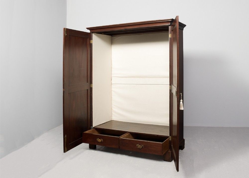 An early George III mahogany press wardrobe featuring two fielded panel doors, a moulded cornice, and bracket feet. View V