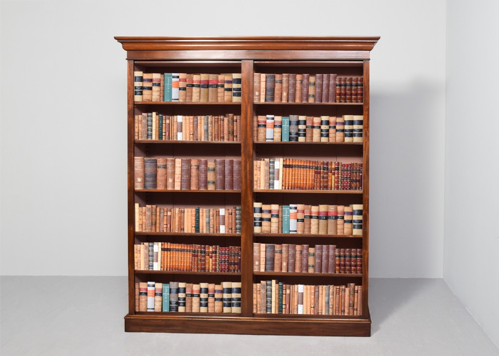 A tall mid-Victorian mahogany open bookcase featuring a double-bay design with adjustable shelves set upon a solid plinth base.