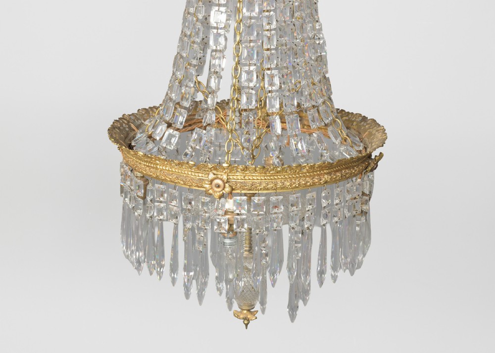 A pair of matching tall crystal and gilt brass chandeliers featuring tapered bead strands, ornate metal coronets, and hanging prism drops. View IV