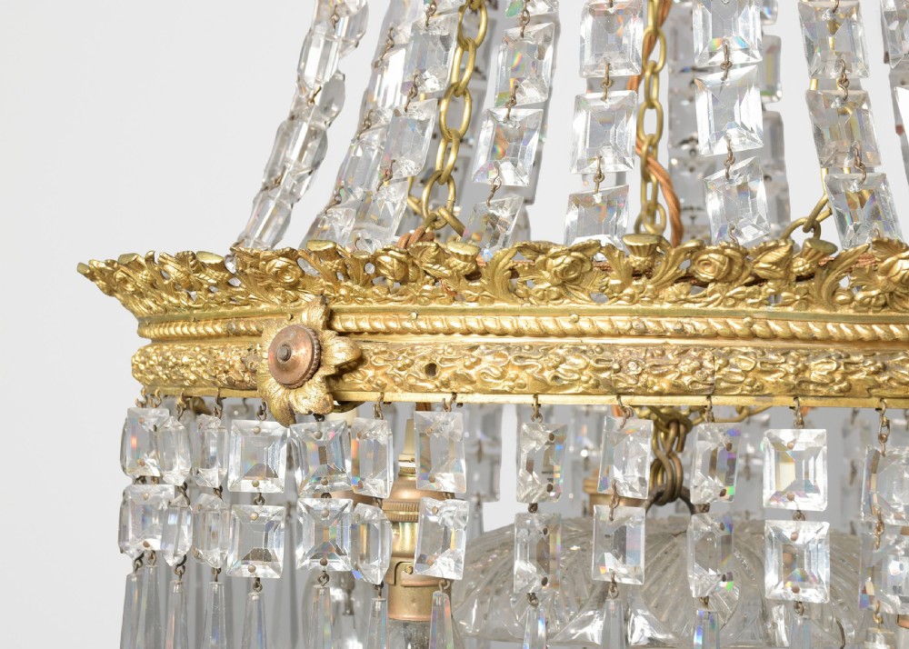 A pair of matching tall crystal and gilt brass chandeliers featuring tapered bead strands, ornate metal coronets, and hanging prism drops. View VII