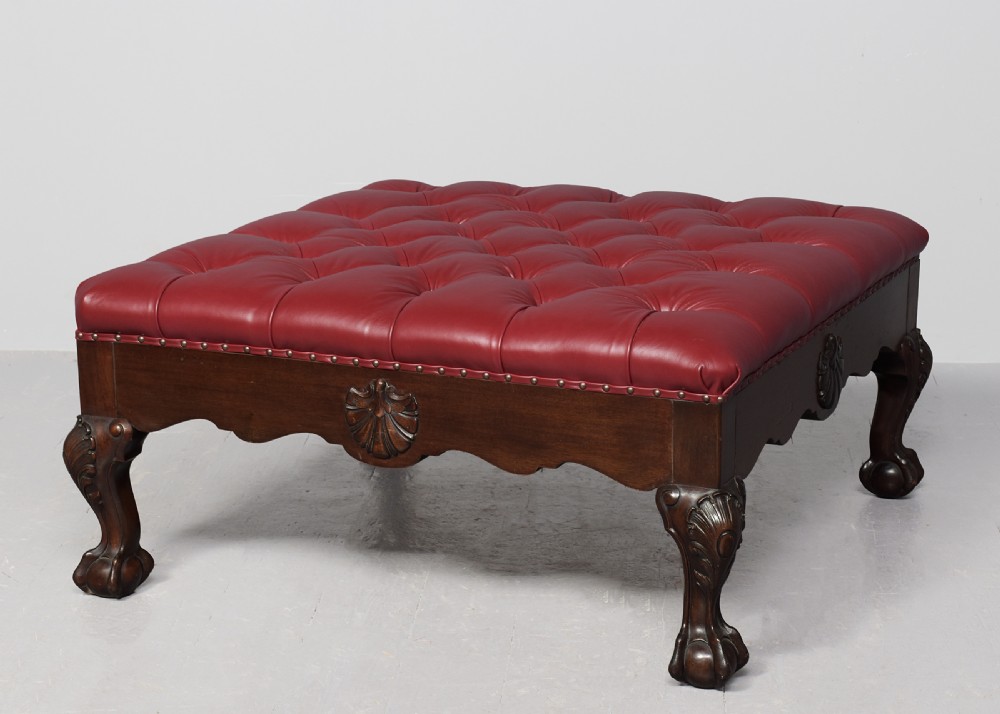 A large square mahogany footstool featuring deep-buttoned burgundy leather upholstery, brass studding, and carved cabriole legs with ball-and-claw feet. View II