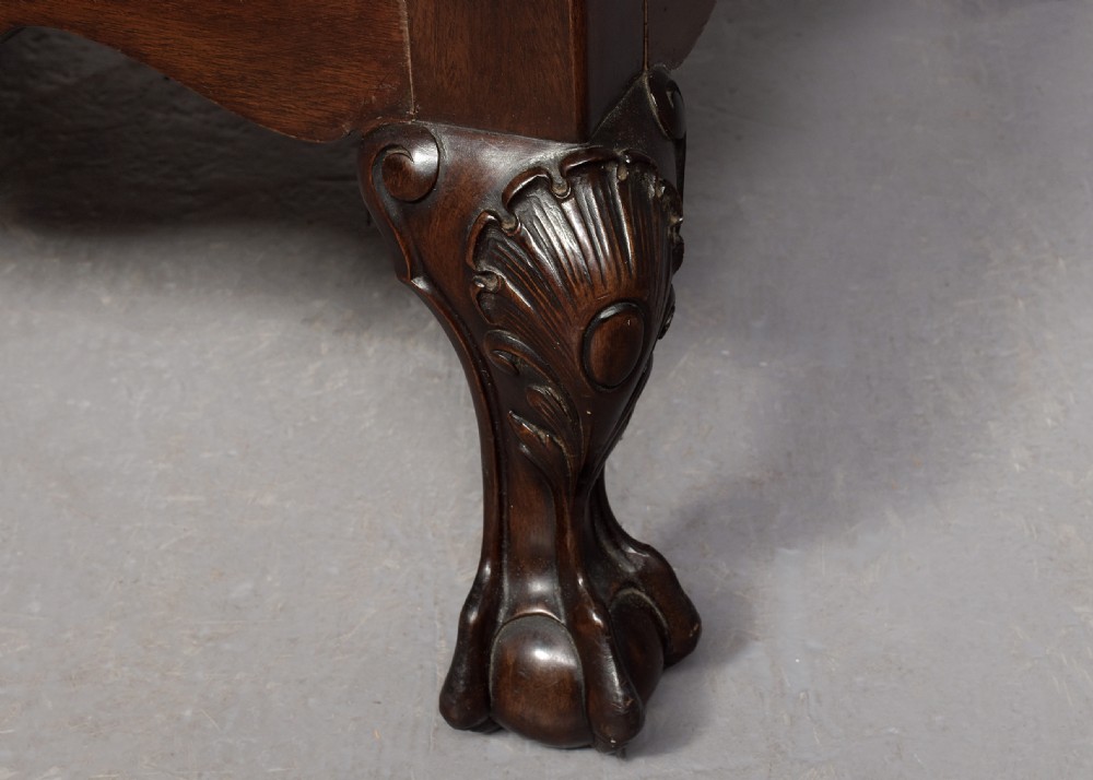 A large square mahogany footstool featuring deep-buttoned burgundy leather upholstery, brass studding, and carved cabriole legs with ball-and-claw feet. View IV