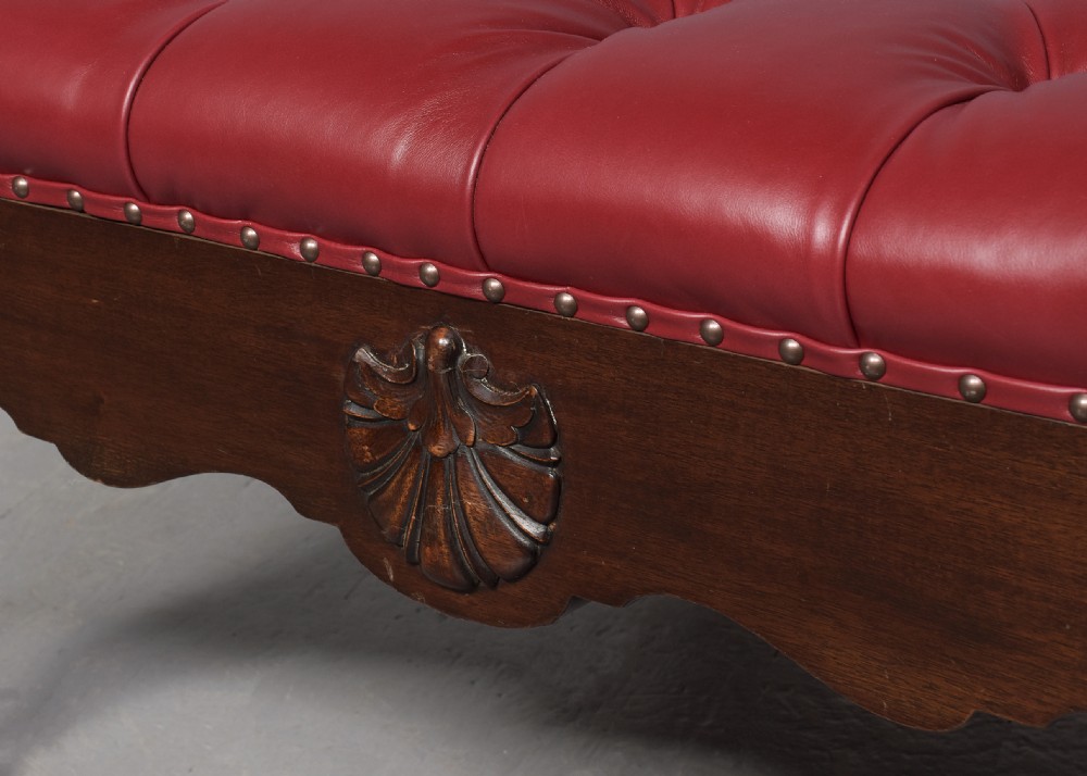 A large square mahogany footstool featuring deep-buttoned burgundy leather upholstery, brass studding, and carved cabriole legs with ball-and-claw feet. View V