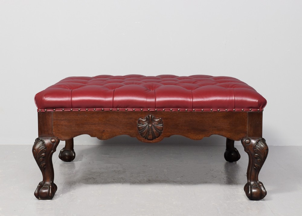 A large square mahogany footstool featuring deep-buttoned burgundy leather upholstery, brass studding, and carved cabriole legs with ball-and-claw feet. View VII