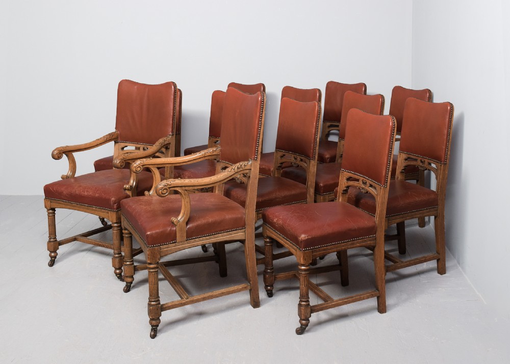 A set of twelve Victorian oak dining chairs upholstered in rich brown leather with brass stud details and turned legs on castors. View II