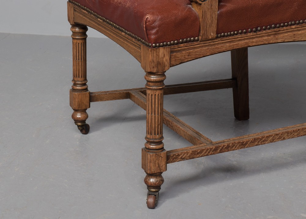 A set of twelve Victorian oak dining chairs upholstered in rich brown leather with brass stud details and turned legs on castors. View V