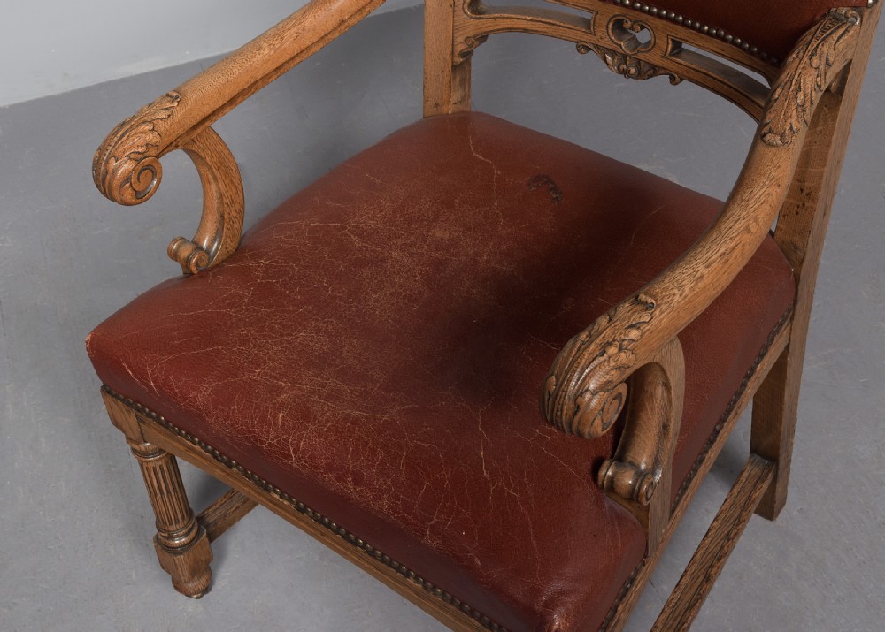 A set of twelve Victorian oak dining chairs upholstered in rich brown leather with brass stud details and turned legs on castors. View VI