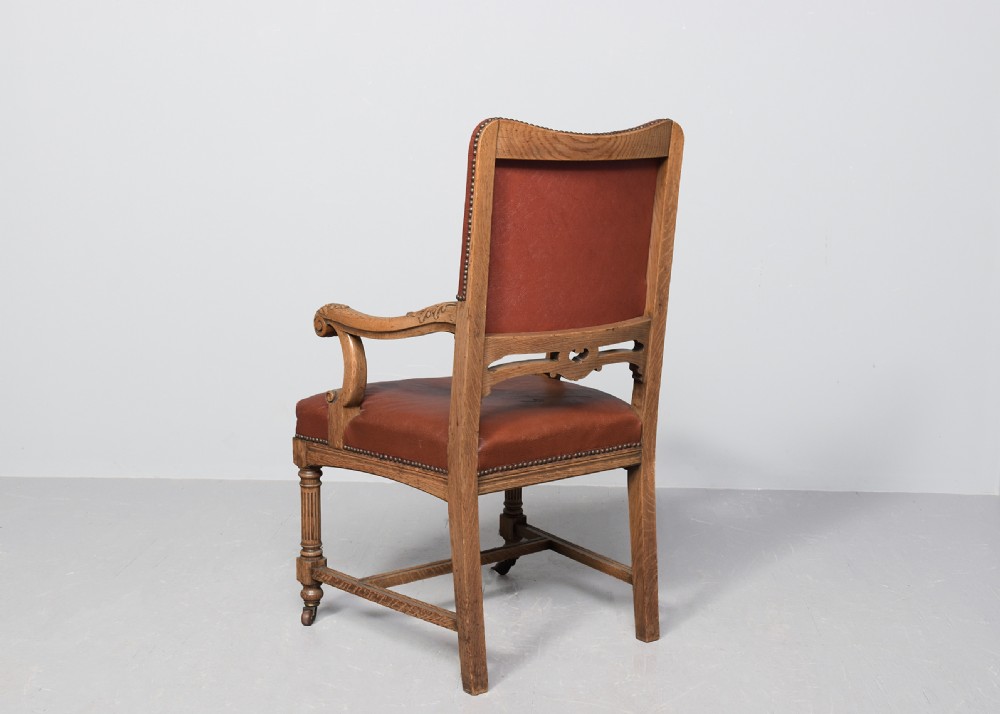 A set of twelve Victorian oak dining chairs upholstered in rich brown leather with brass stud details and turned legs on castors. View VII
