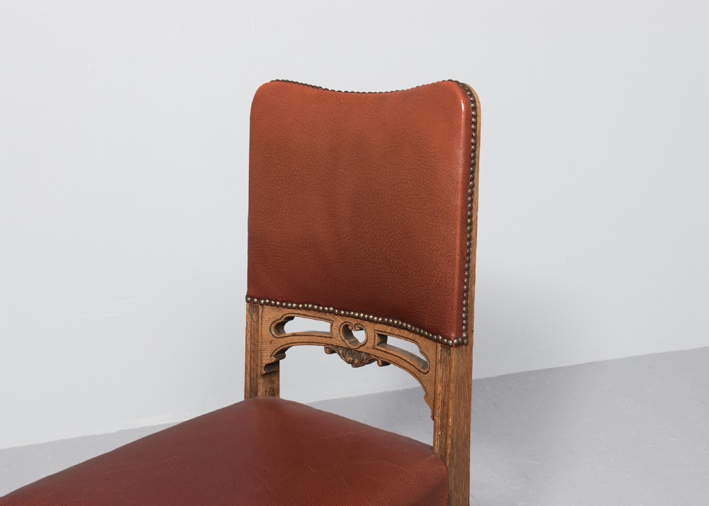 A set of twelve Victorian oak dining chairs upholstered in rich brown leather with brass stud details and turned legs on castors. View IX