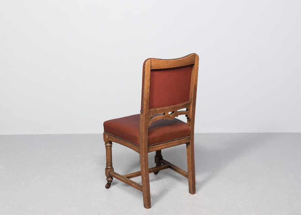 A set of twelve Victorian oak dining chairs upholstered in rich brown leather with brass stud details and turned legs on castors. View XII
