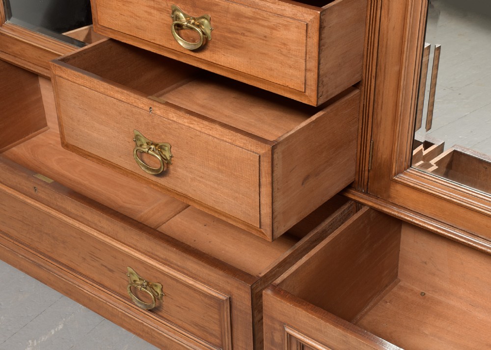 A straight-grained walnut three-section wardrobe with two tall mirrored doors flanking a central column containing a small cupboard, open shelf, and multiple drawers. View V