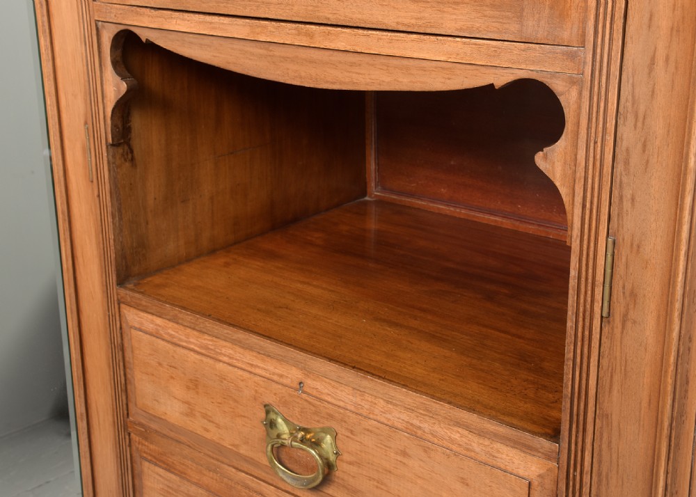A straight-grained walnut three-section wardrobe with two tall mirrored doors flanking a central column containing a small cupboard, open shelf, and multiple drawers. View VIII