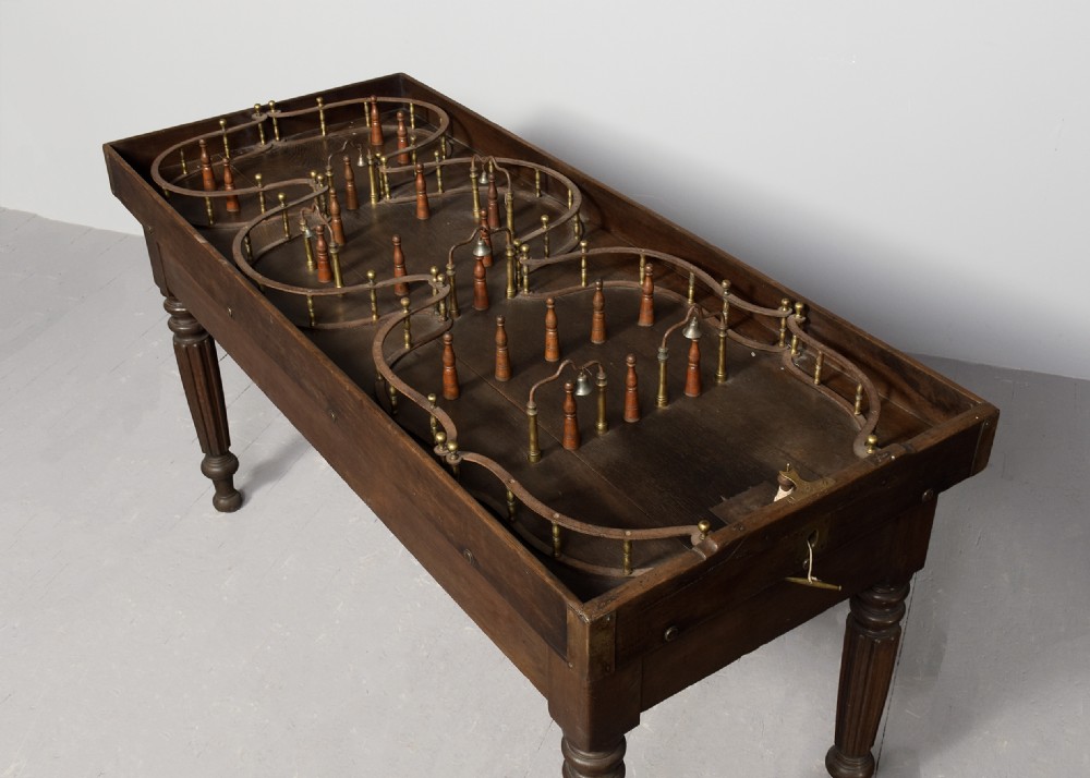 A George IV freestanding dark oak skittles game table featuring turned fluted legs and internal brass game guides. View II