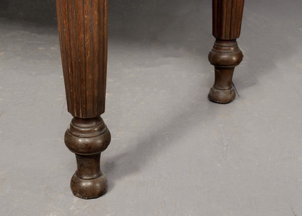 A George IV freestanding dark oak skittles game table featuring turned fluted legs and internal brass game guides. View IX
