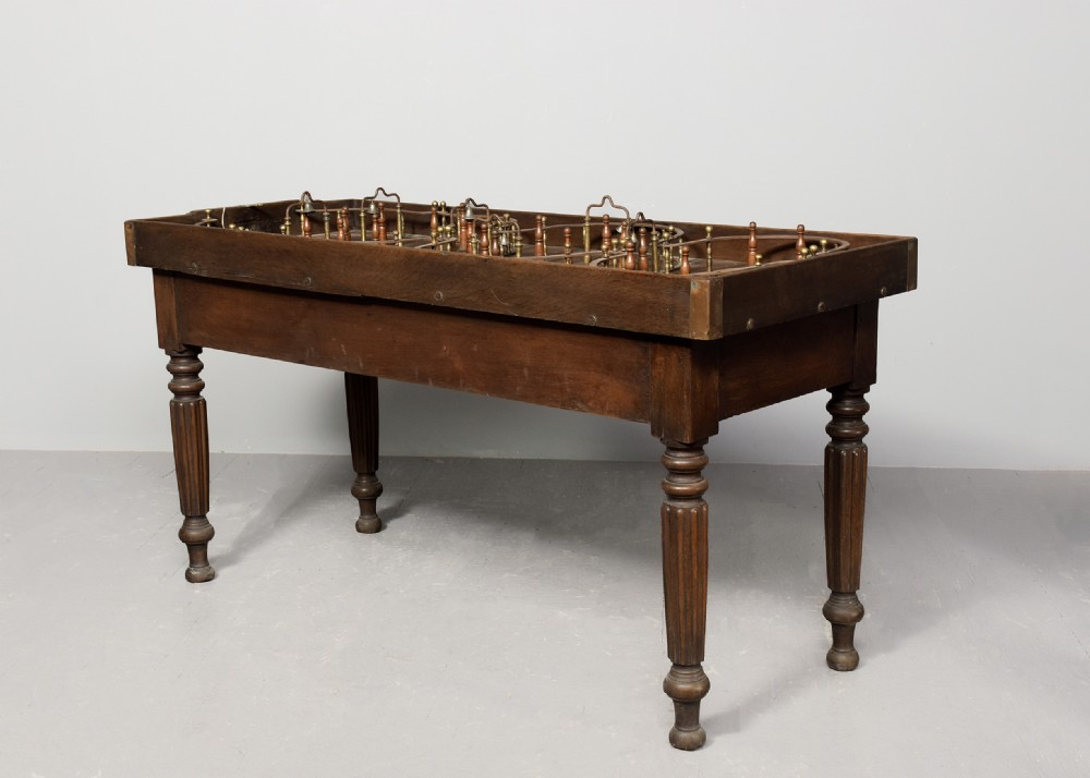 A George IV freestanding dark oak skittles game table featuring turned fluted legs and internal brass game guides. View X