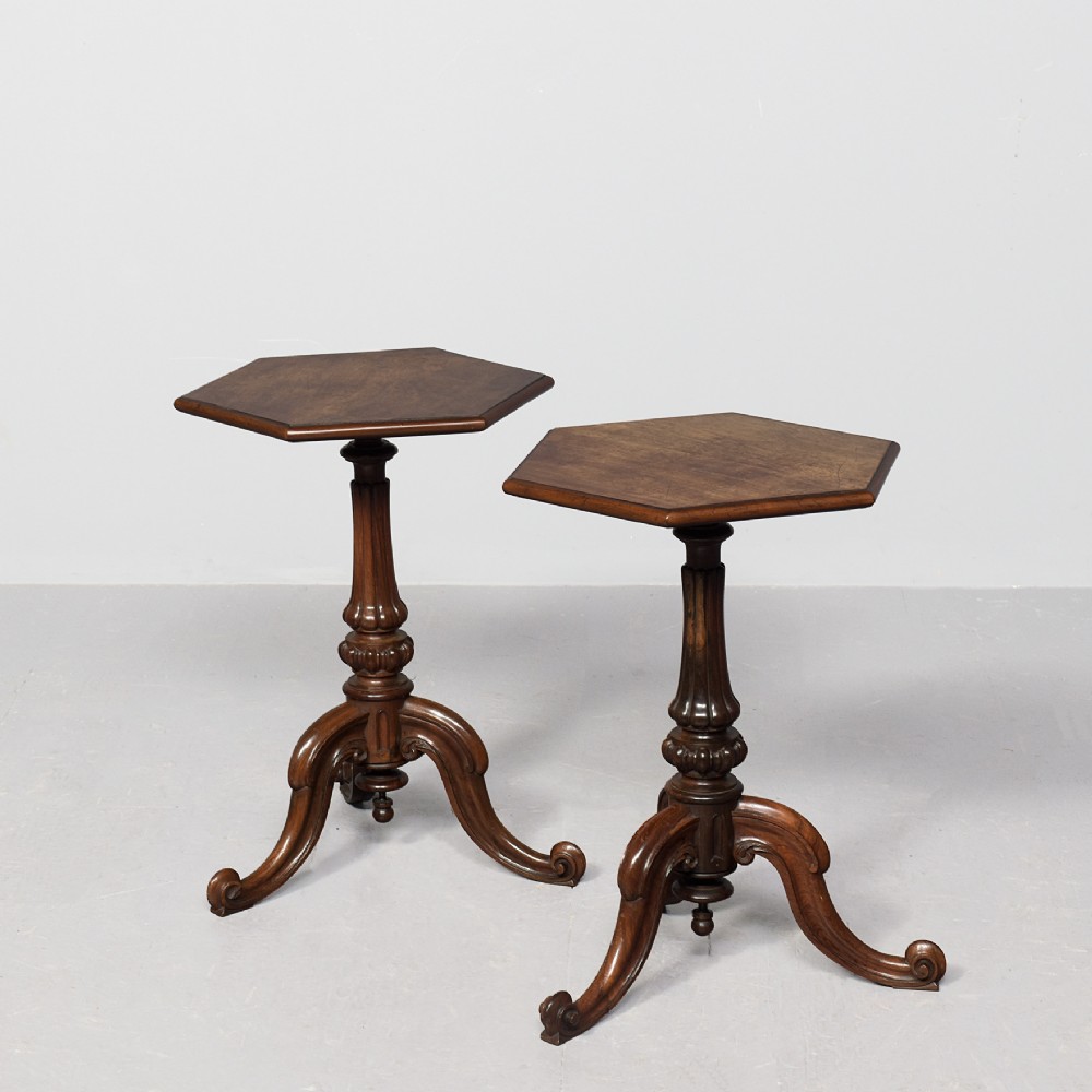 A pair of rosewood occasional tables featuring hexagonal tops, turned carved pedestals, and scrolled tripod legs.