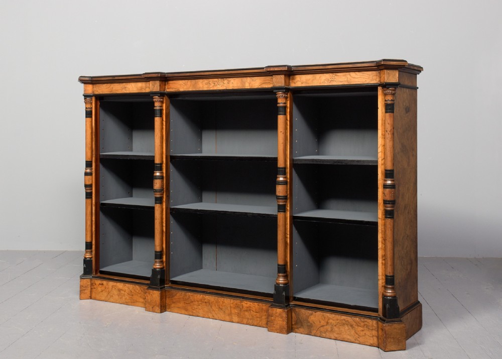 A low three-section open bookcase made of figured burr walnut featuring ebonised turned columns and a grey painted interior. View II