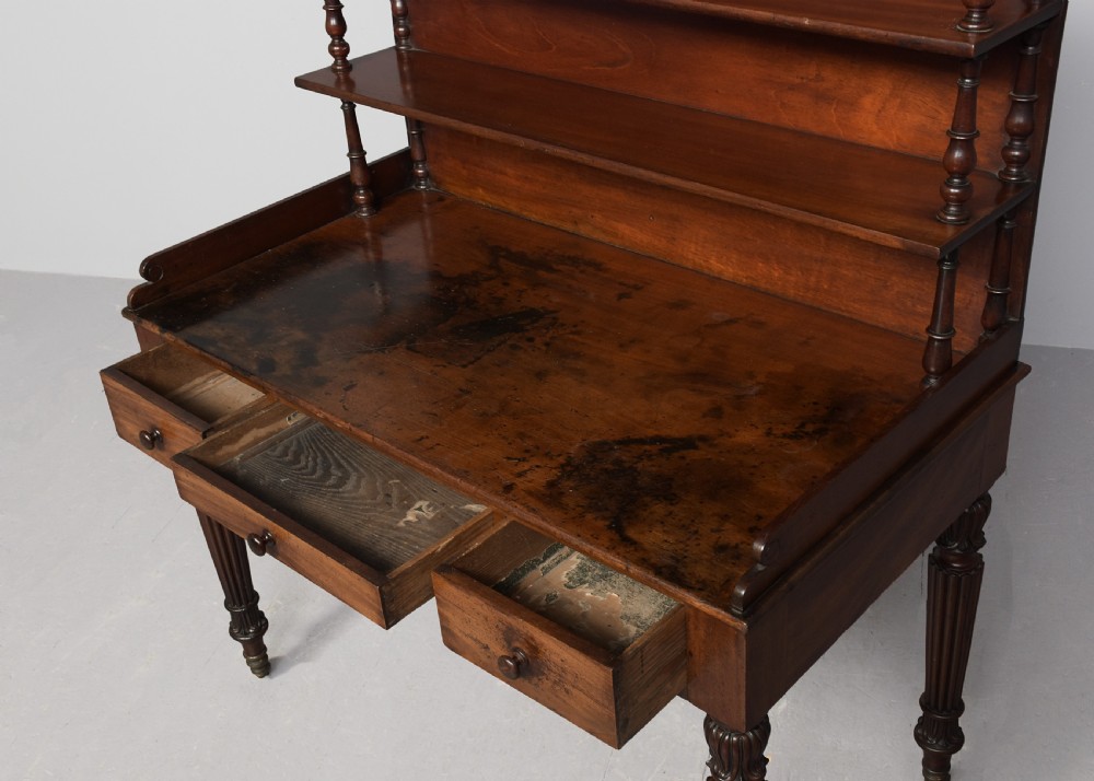 A Regency mahogany writing desk featuring a tiered shelving gallery, three frieze drawers, fluted reeded legs, and brass castors. View III