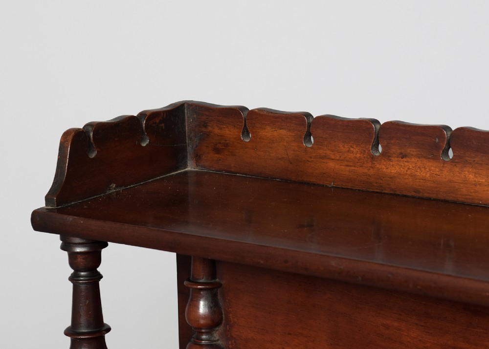 A Regency mahogany writing desk featuring a tiered shelving gallery, three frieze drawers, fluted reeded legs, and brass castors. View IV