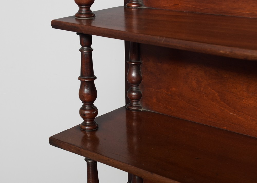 A Regency mahogany writing desk featuring a tiered shelving gallery, three frieze drawers, fluted reeded legs, and brass castors. View V