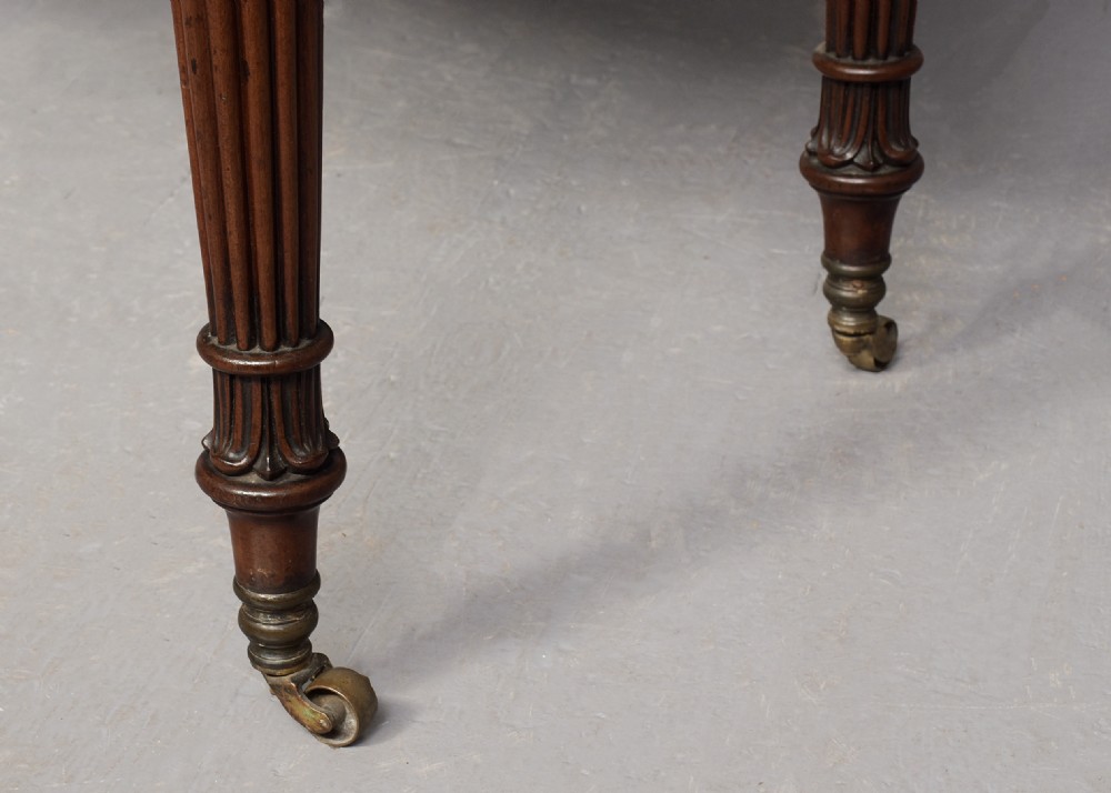 A Regency mahogany writing desk featuring a tiered shelving gallery, three frieze drawers, fluted reeded legs, and brass castors. View VI