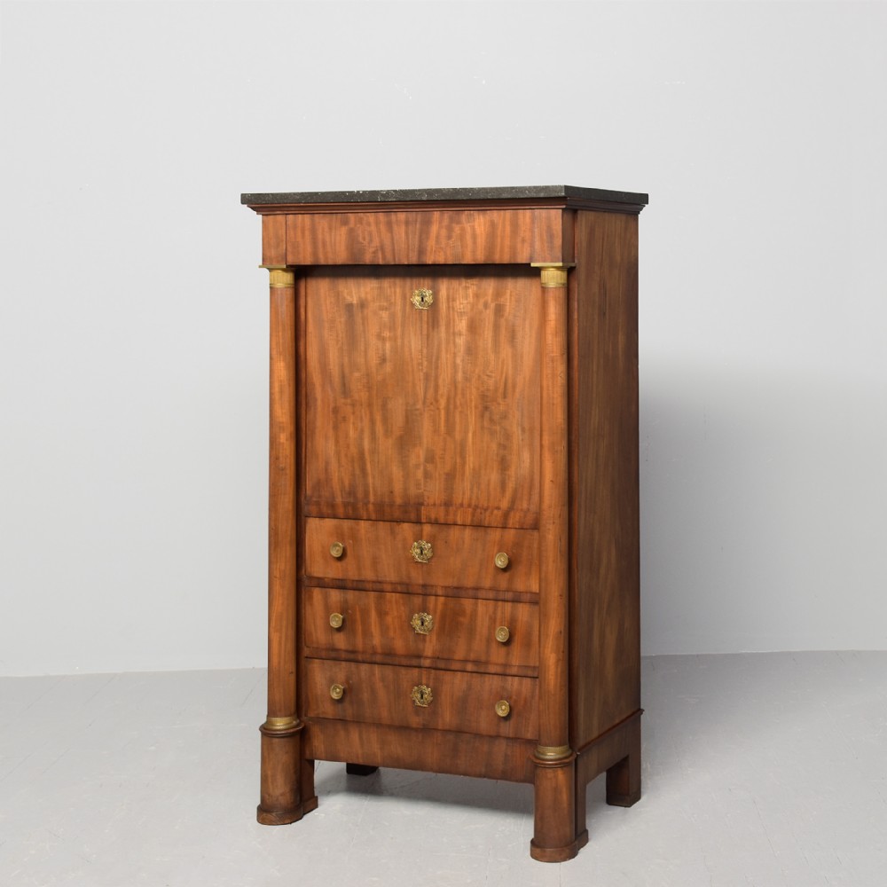 A tall mahogany secretaire abattant featuring a dark marble top, a drop-front writing panel flanked by turned columns, and three lower drawers with brass handles.