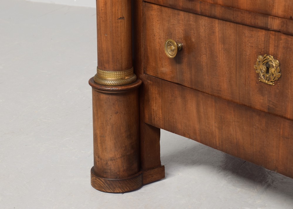 A tall mahogany secretaire abattant featuring a dark marble top, a drop-front writing panel flanked by turned columns, and three lower drawers with brass handles. View II