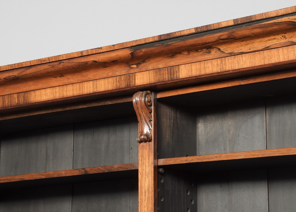 A tall William IV rosewood open bookcase featuring two upper shelf sections over lower bays with carved corbels and a solid plinth base. View IV