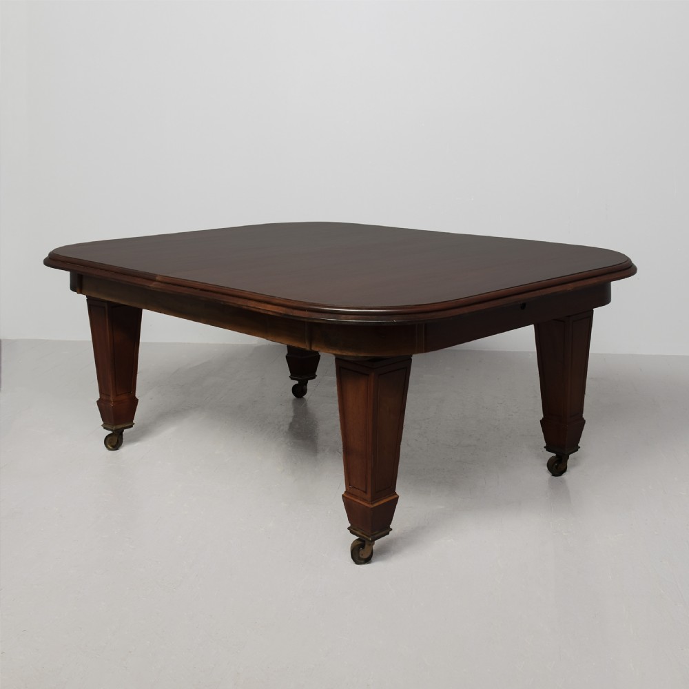 A large rectangular Victorian mahogany extending dining table featuring rounded corners, faceted tapered legs, a fifth central support leg, and brass castors.