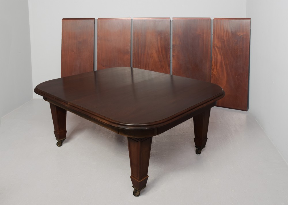 A large rectangular Victorian mahogany extending dining table featuring rounded corners, faceted tapered legs, a fifth central support leg, and brass castors. View VI