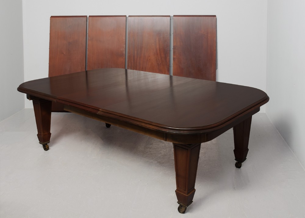A large rectangular Victorian mahogany extending dining table featuring rounded corners, faceted tapered legs, a fifth central support leg, and brass castors. View VII