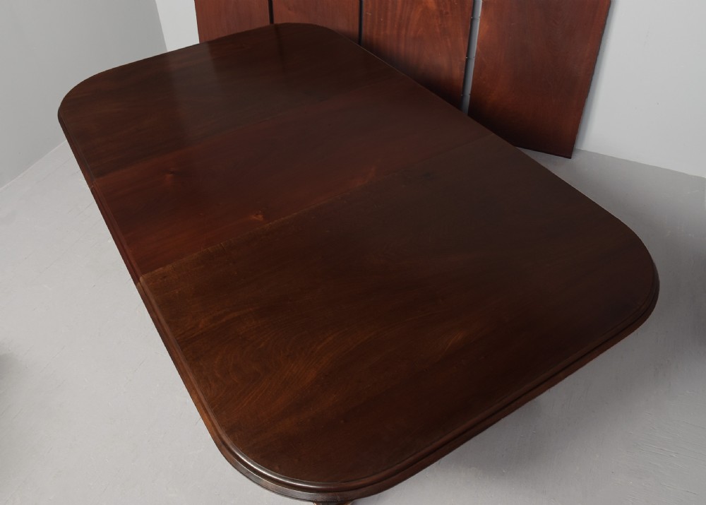 A large rectangular Victorian mahogany extending dining table featuring rounded corners, faceted tapered legs, a fifth central support leg, and brass castors. View VIII