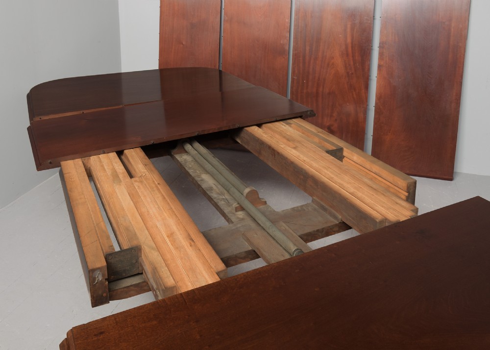 A large rectangular Victorian mahogany extending dining table featuring rounded corners, faceted tapered legs, a fifth central support leg, and brass castors. View XI