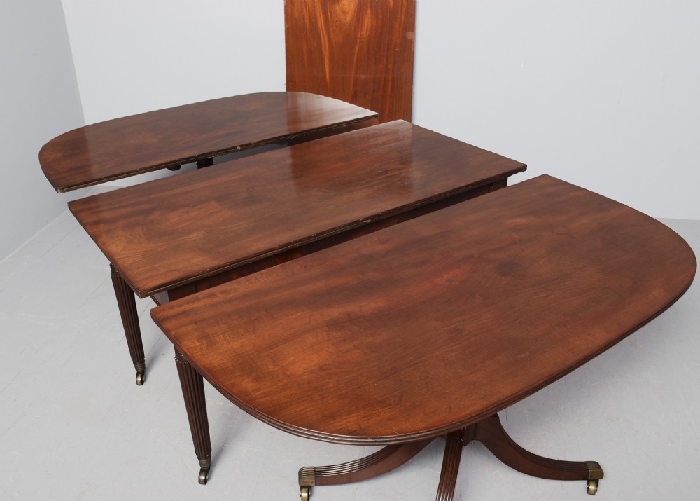 A Regency mahogany twin-pedestal extending dining table supported by reeded splayed legs with brass castors. View III