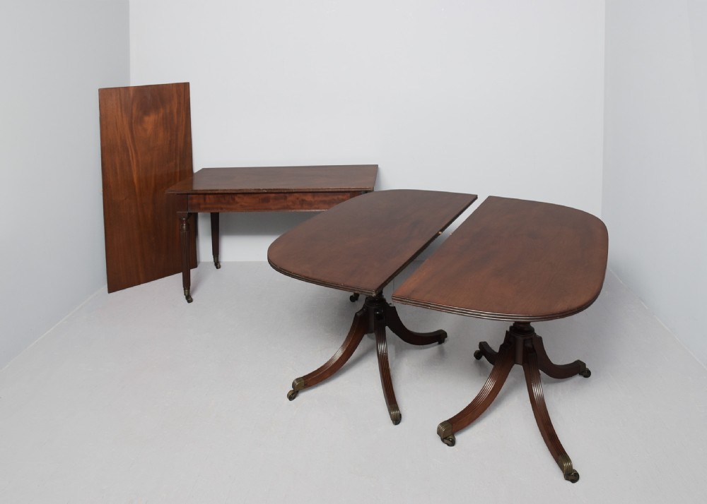 A Regency mahogany twin-pedestal extending dining table supported by reeded splayed legs with brass castors. View V