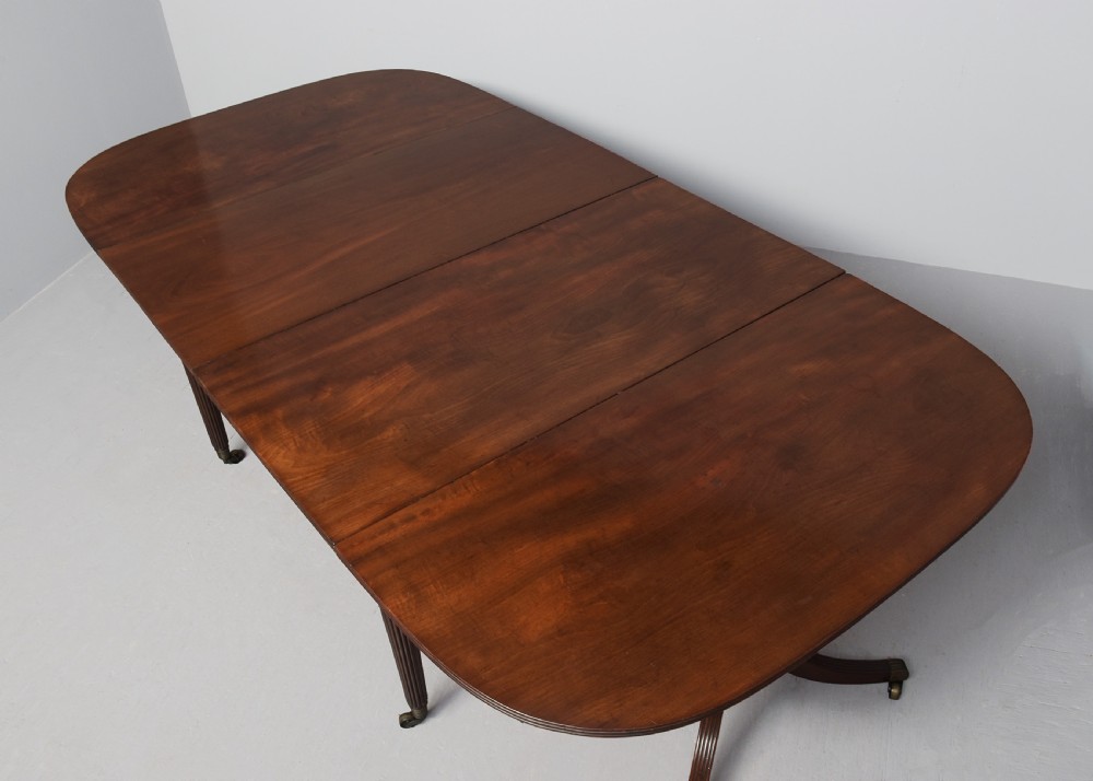 A Regency mahogany twin-pedestal extending dining table supported by reeded splayed legs with brass castors. View IX