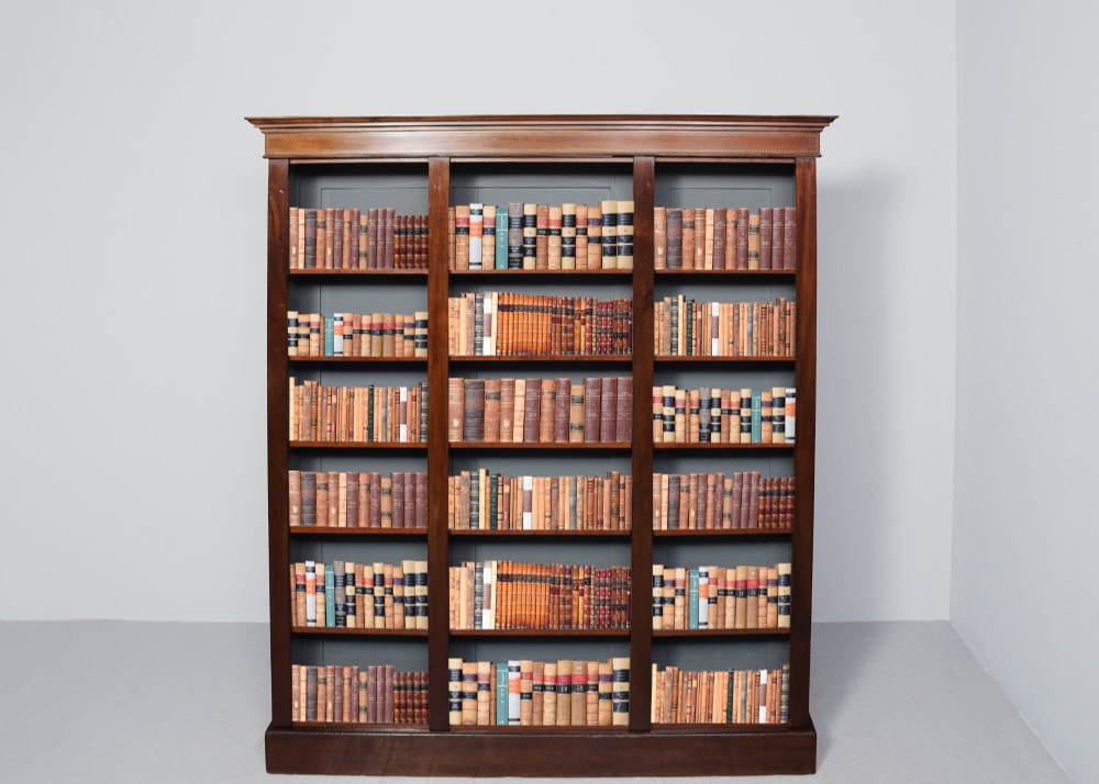 A large three-section mahogany open bookcase featuring adjustable shelves and fine inlay detailing along the top cornice.