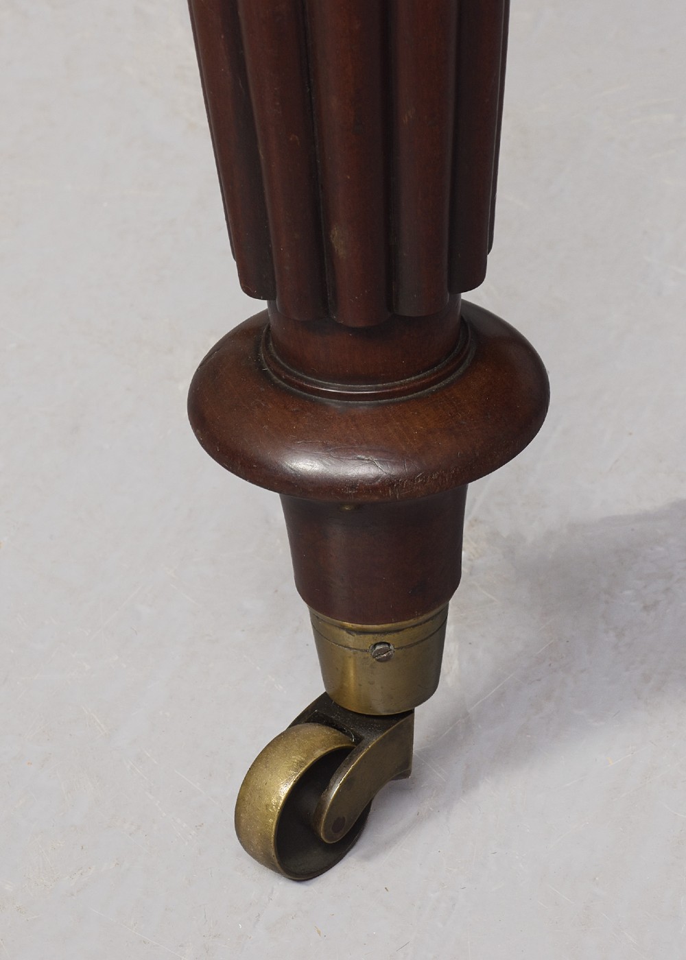 A rectangular George IV mahogany extending dining table with rounded corners, reeded turned legs, and brass castors. View VIII