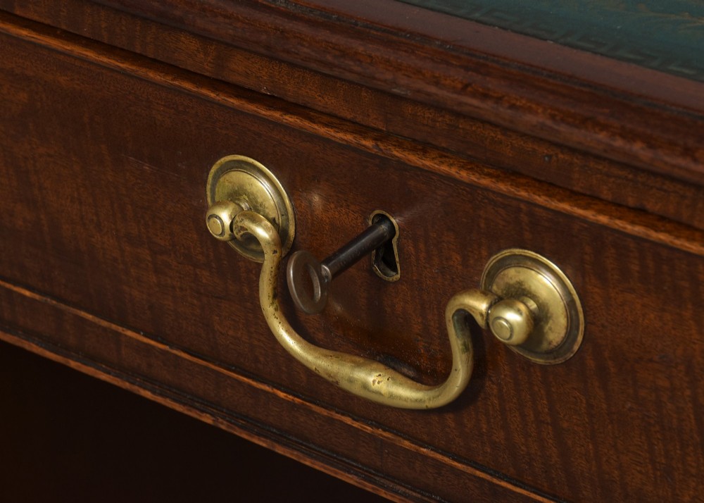 A large George III mahogany partners desk featuring a green leather writing surface, dual pedestals with brass swan-neck handles, and bracket feet. View III