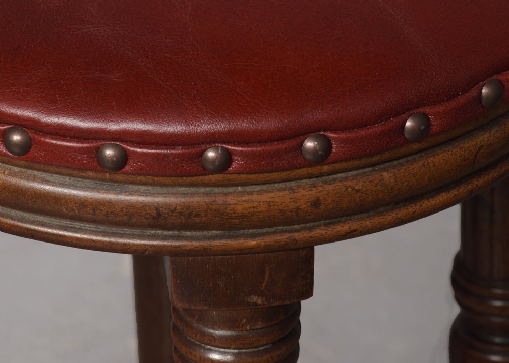 A tall George III circular wooden stool featuring four turned legs, a floral tapestry seat, and brass stud detailing along the rim. View II