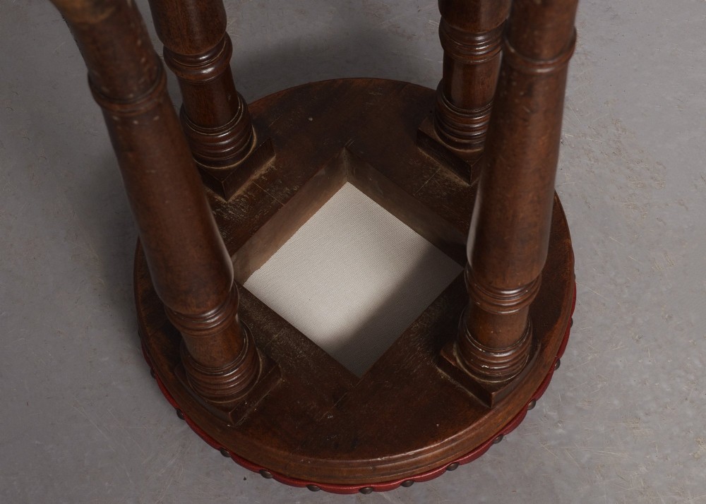 A tall George III circular wooden stool featuring four turned legs, a floral tapestry seat, and brass stud detailing along the rim. View III