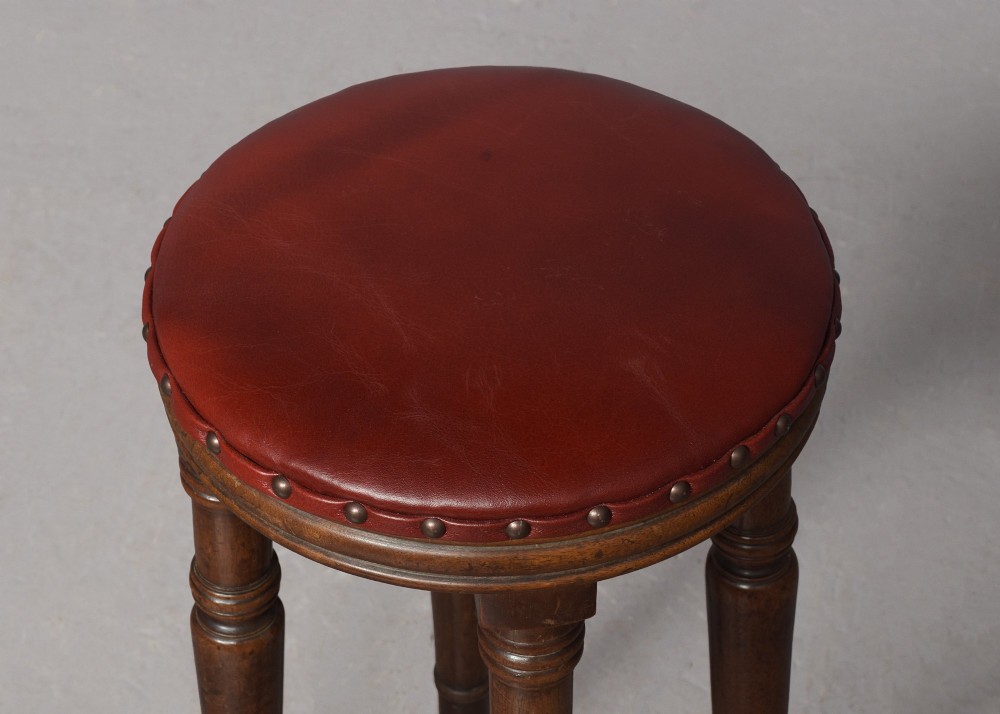 A tall George III circular wooden stool featuring four turned legs, a floral tapestry seat, and brass stud detailing along the rim. View IV