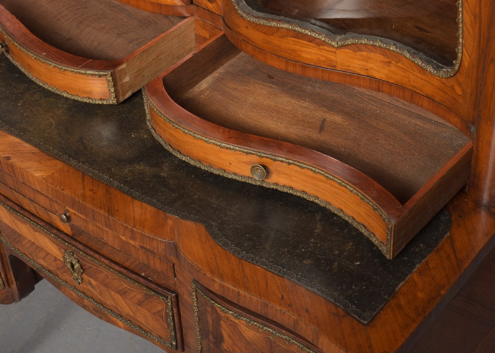 A nineteenth-century French style kingwood and walnut writing desk featuring an upper glazed display cabinet, brass top gallery, cabriole legs, and gilded metal mounts. View IV