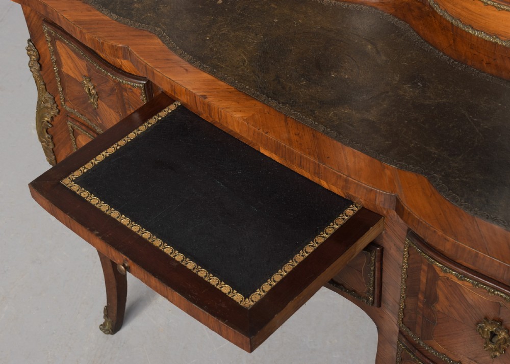 A nineteenth-century French style kingwood and walnut writing desk featuring an upper glazed display cabinet, brass top gallery, cabriole legs, and gilded metal mounts. View VI